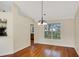 Bright dining room with hardwood floors, a hanging light fixture, and a large window overlooking trees at 5410 Lenox Park Pl, Buford, GA 30518