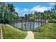 Community tennis court featuring a fenced perimeter, paved walkway, and a bench for relaxation, all set amidst lush green surroundings at 5410 Lenox Park Pl, Buford, GA 30518