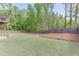 Large backyard with green grass, mature trees, privacy fence, with a deck and patio area for outdoor enjoyment at 1625 Brisbane Dr, Dacula, GA 30019