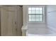 Bathroom featuring a glass-enclosed shower, a soaking tub, and a bright window at 1625 Brisbane Dr, Dacula, GA 30019