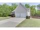 Side view of a lovely home featuring a two-car garage and a long driveway lined with green grass at 1625 Brisbane Dr, Dacula, GA 30019