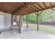 View of the covered patio with brick flooring, outdoor seating and stairs to the deck, overlooking the fenced backyard at 1625 Brisbane Dr, Dacula, GA 30019