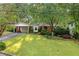 Quaint brick house featuring a manicured front lawn, mature trees, and covered carport at 1866 Wildwood Ne Pl, Atlanta, GA 30324