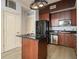 Compact kitchen with black appliances, dark wood cabinets, and an island with black countertop at 57 Forsyth Nw St # 12E, Atlanta, GA 30303