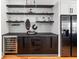 Stylish wet bar with wine refrigerator, black cabinetry, open shelving, and chevron patterned backsplash at 210 Locust Ne St, Atlanta, GA 30317
