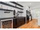 Inviting wet bar with wine refrigerator, black cabinetry, open shelving, and chevron patterned backsplash at 210 Locust Ne St, Atlanta, GA 30317