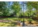 Private backyard featuring a lush lawn, bordered by mature trees, a wooden fence, and stone steps at 2977 Parkridge Ne Dr, Brookhaven, GA 30319