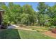 Well-manicured backyard with mature trees, play area, patio, and stone walkway at 1922 Olde Village Run, Dunwoody, GA 30338