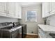 Modern laundry room with front-load washer/dryer, white cabinets, and a storage shelf at 1922 Olde Village Run, Dunwoody, GA 30338