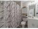 Bathroom with a marble pattern shower curtain, white vanity and decorative shelving for storage at 230 Wild Barley Way, Loganville, GA 30052