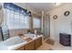 Bathroom featuring a soaking tub, separate glass shower and neutral tile surround at 230 Wild Barley Way, Loganville, GA 30052