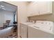 Laundry area equipped with a washer and dryer, white cabinets, and an open doorway at 230 Wild Barley Way, Loganville, GA 30052