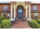 Grand front entrance with double doors, columns, and well-manicured landscaping and brick stairs at 5010 Heardmont Trace Rd, Cumming, GA 30028