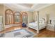 Elegant main bedroom boasts large windows, hardwood floors, and a luxurious four-poster bed, creating a serene retreat at 5010 Heardmont Trace Rd, Cumming, GA 30028