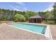 The in-ground pool sits adjacent to an outbuilding and is surrounded by a brick patio at 5010 Heardmont Trace Rd, Cumming, GA 30028