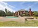 A large in-ground pool and hot tub sit on a stone patio behind an elegant brick home at 5010 Heardmont Trace Rd, Cumming, GA 30028