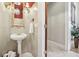 Stylish powder room featuring a pedestal sink, decorative mirror, and tiled walls at 5010 Heardmont Trace Rd, Cumming, GA 30028