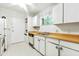 Efficient kitchen featuring white cabinetry, wood countertops, and integrated appliances, including a stackable washer/dryer unit at 1111 Clairemont Ave # J6, Decatur, GA 30030