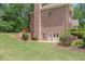 A manicured backyard with lush lawn, mature trees, terraced planting beds, and a brick home at 1180 Oxford Dr, Conyers, GA 30013