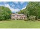 Traditional brick home featuring a well-manicured lawn and mature trees, providing curb appeal and privacy at 1180 Oxford Dr, Conyers, GA 30013