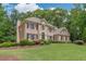 Brick home featuring a well-maintained lawn, mature trees, and manicured shrubbery at 1180 Oxford Dr, Conyers, GA 30013