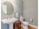 Stylish powder room boasting a pedestal sink, round mirror, and wood-look floors at 1180 Oxford Dr, Conyers, GA 30013
