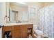 Bathroom features a wood vanity, sink, mirror, and tiled shower with curtain at 1057 Cotton Oak Dr, Lawrenceville, GA 30045