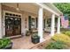 Inviting front porch featuring brick flooring, columns, comfortable seating, and stylish accents at 215 Scott Xing, Roswell, GA 30076