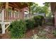 View of covered back porch with stairs, wood railing, red siding, and mature landscaping at 604 Mead Se St, Atlanta, GA 30312