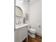 Stylish powder room featuring a white vanity with sink, round mirror, and hardwood flooring at 604 Mead Se St, Atlanta, GA 30312