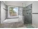 Bright bathroom features a tub with jets under a large window and a glass shower at 7010 Beloit Pl, Roswell, GA 30075