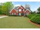 Beautiful two-story brick home featuring lush green lawn and mature landscaping at 7010 Beloit Pl, Roswell, GA 30075