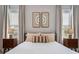 Bedroom with neutral-colored bedding and two symmetrical framed artworks centered between the windows at 2467 Davis Se Dr, Smyrna, GA 30080