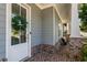 Close-up of a gray-sided porch with brick base, a white door, and a cozy seating area at 2467 Davis Se Dr, Smyrna, GA 30080