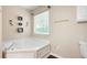Bright white soaking tub in a modern bathroom with decorative wall accents and a window at 174 Cannon Pl, Dallas, GA 30157