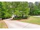 Charming front exterior with a long driveway, lush lawn, and mature trees at 174 Cannon Pl, Dallas, GA 30157