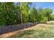 Fenced backyard with lush green grass and mature trees, offering privacy and a serene setting at 3747 Silvery Way, Powder Springs, GA 30127