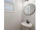 Modern powder room with a pedestal sink, a round mirror, and a window for natural light at 3747 Silvery Way, Powder Springs, GA 30127