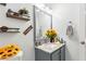 This is a stylish bathroom featuring a gray vanity, a framed mirror, and decorative shelves with plants at 1010 Augusta Woods Dr, Douglasville, GA 30134