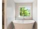 Bright bathroom featuring a modern white bathtub with a large window overlooking the yard at 1541 Pontiac Se Pl, Atlanta, GA 30315