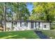 Charming home featuring a white painted brick exterior, black shutters, and a well-manicured lawn surrounded by mature trees at 2905 Gresham Se Rd, Atlanta, GA 30316