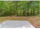 Backyard featuring a grassy area with mature trees and a concrete patio for outdoor enjoyment at 4087 Rosebud Park Dr, Snellville, GA 30039