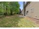 Backyard featuring a grassy area with mature trees and a concrete patio for outdoor enjoyment at 4087 Rosebud Park Dr, Snellville, GA 30039