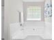 Bright bathroom featuring a soaking tub and a window, with a blue flower painting above the tub at 4087 Rosebud Park Dr, Snellville, GA 30039