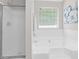 Bright bathroom featuring a shower with glass door, large tub and a window at 4087 Rosebud Park Dr, Snellville, GA 30039