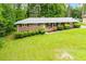 Brick home featuring a well-manicured lawn, lush bushes, and a charming facade under a clear sky at 3047 E Anderson E Dr, Lithia Springs, GA 30122