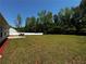 Expansive backyard with a well-maintained lawn, patio, chairs, and white picket fence under a clear blue sky at 20 Chapman Way, Covington, GA 30016