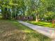 Single-story brick home with concrete driveway, set amidst a lush, green lawn and mature trees at 233 Banberry Se Dr, Atlanta, GA 30315