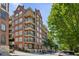Brick apartment building featuring balconies and green trees lining the street in a neighborhood setting at 77 Peachtree Ne Pl # 107, Atlanta, GA 30309