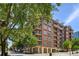 A brick apartment building featuring multiple balconies and lush, green trees surrounding the property at 77 Peachtree Ne Pl # 107, Atlanta, GA 30309